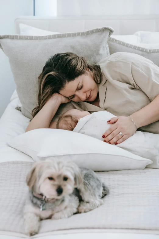 a woman laying on top of a bed next to a dog, maternity feeling, profile image, australian, husband wife and son