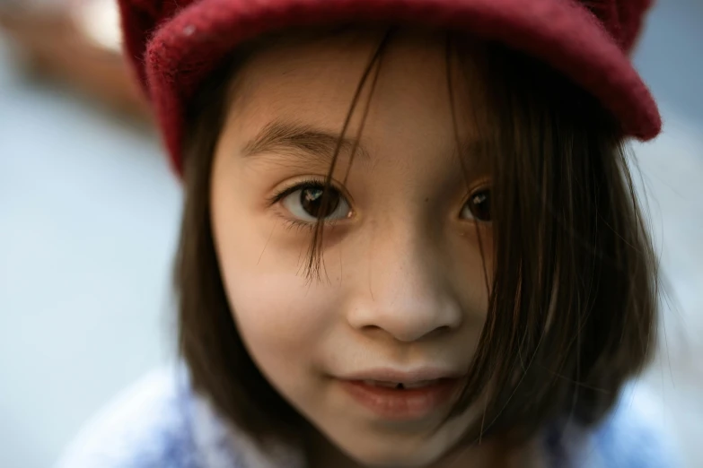 a close up of a child wearing a red hat, inspired by Nara Yoshitomo, pexels contest winner, girl with dark brown hair, looking straight to camera, high quality image, ::