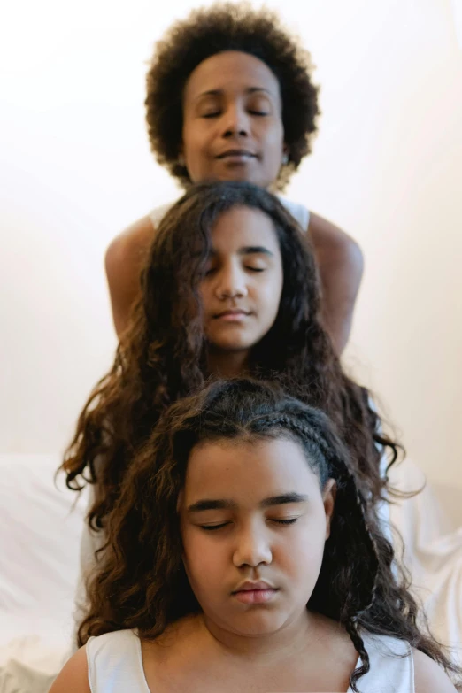 a group of women sitting on top of a bed, three heads, meditative sacral pose, kids, photo of a black woman