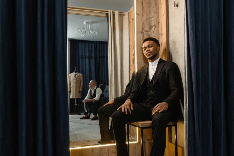 a man sitting on a stool in front of a mirror, tailored clothing, wax figure, george pemba, thumbnail