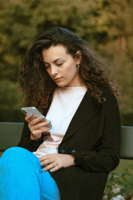 a woman sitting on a bench looking at her cell phone, pexels, happening, brown curly hair, square, 1 2 9 7, dark. no text