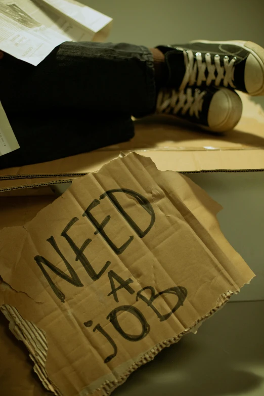 a person sitting on top of a cardboard box, by Elsa Bleda, reddit, graffiti, bed is not made, closeup photograph, banner, acab