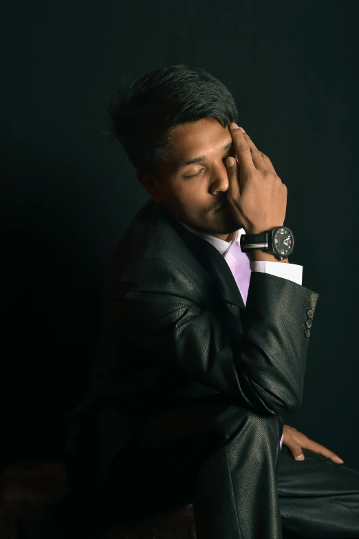 a man in a suit sitting on a chair, an album cover, inspired by Yousuf Karsh, pexels contest winner, romanticism, wearing a watch, candid!! dark background, thinking pose, sleepy feeling