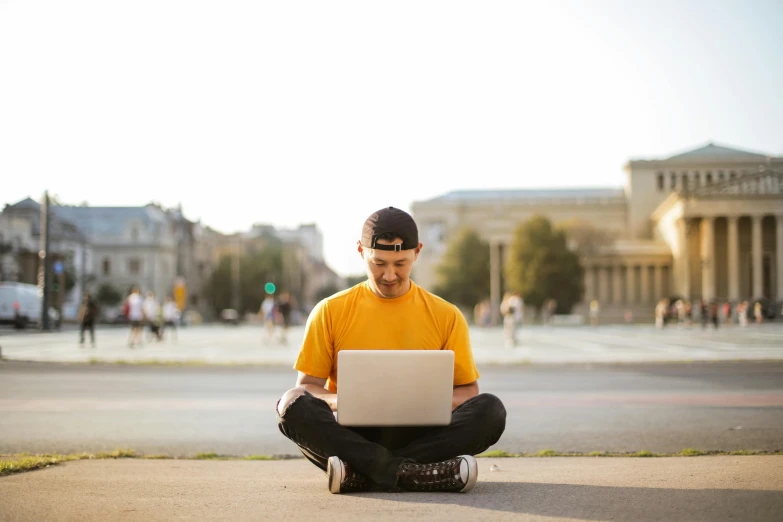 a man sitting on the ground using a laptop, by Julia Pishtar, yellow, college, in a square, high quality upload