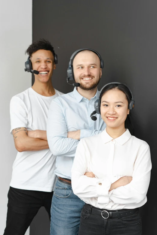 a group of people standing next to each other, wearing a headset, on a gray background, varying ethnicities, slightly smiling