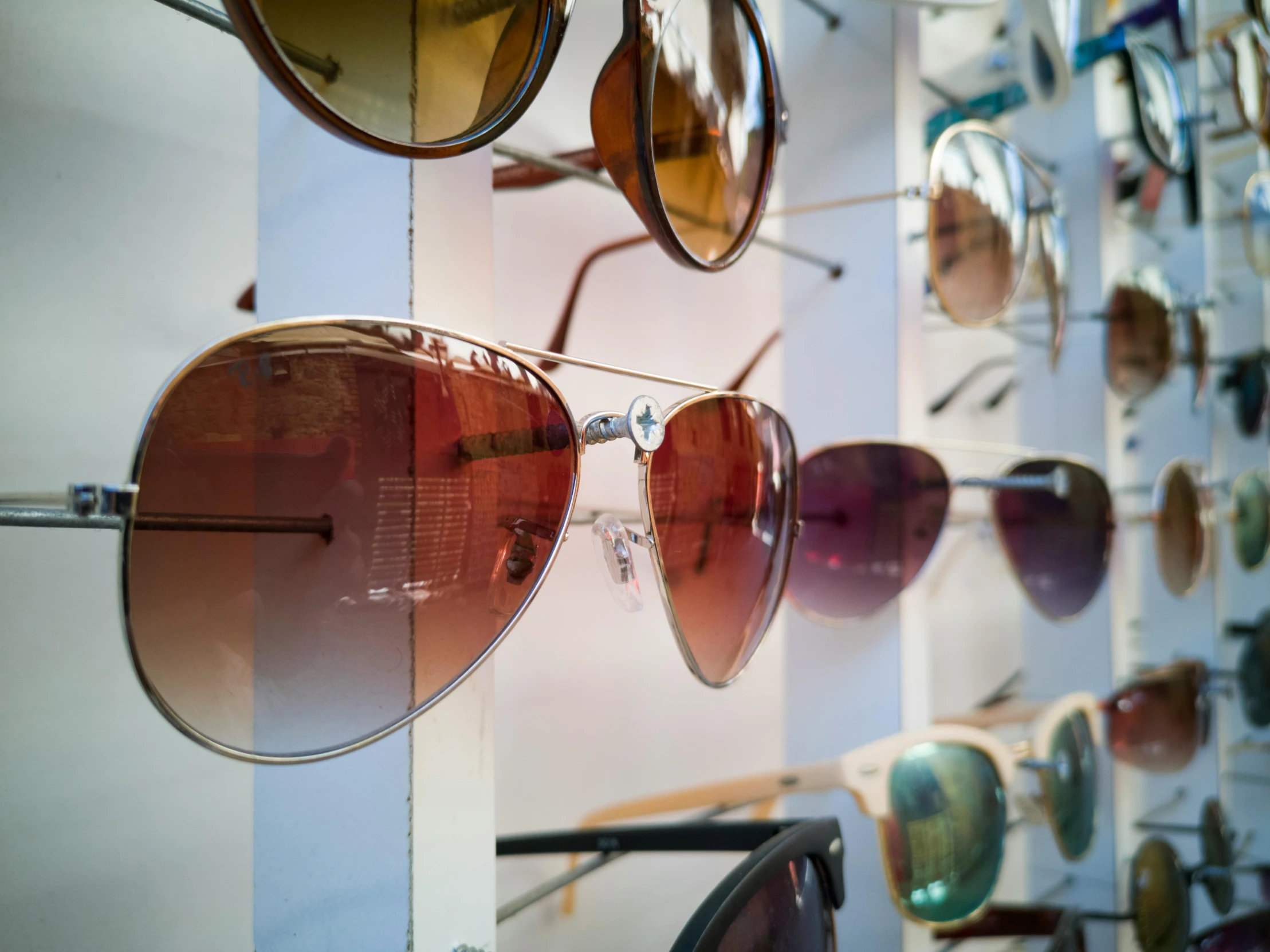 a wall filled with lots of different colored sunglasses, by Lee Loughridge, trending on unsplash, fan favorite, gradient brown to red, closeup - view, aviators