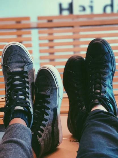 two people sitting on a bench with their feet up, by Niko Henrichon, pexels contest winner, realism, sneaker shoes, indoor picture, with black, in a row