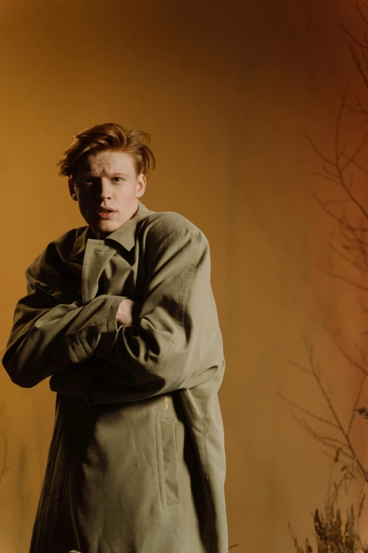 a man is standing with his arms crossed, an album cover, by Lee Gatch, trending on pexels, renaissance, ginger hair, he wears a big coat, pale glowing skin, corduroy