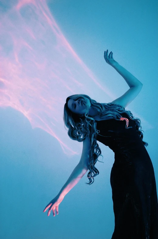 a woman in a black dress is flying through the air, an album cover, by Matt Cavotta, pexels contest winner, red and blue black light, petra collins, flowing glowing hair, dramatic standing pose