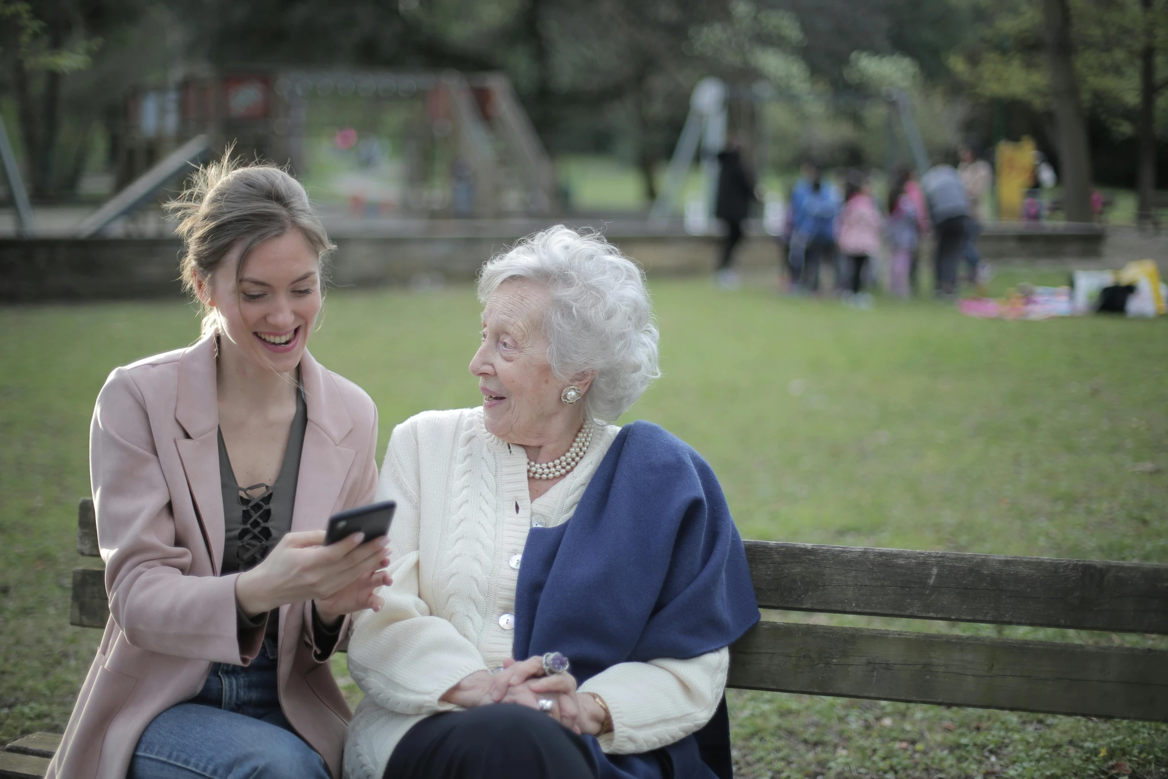 a woman sitting next to an older woman on a bench, happening, shot on alexa, a park, smiling playfully, unedited