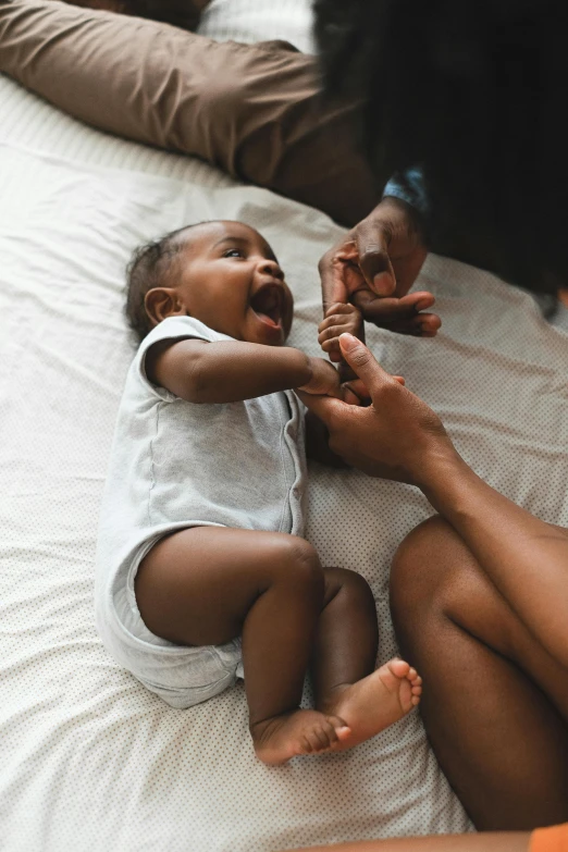 a woman playing with a baby on a bed, pexels contest winner, brown skinned, holding hands, tiny mouth, 1 2 9 7