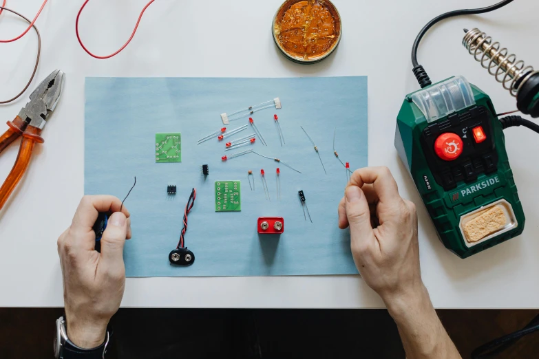 a person holding a pair of scissors over a piece of paper, complicated circuits and wires, ingredients on the table, on a canva, transistors