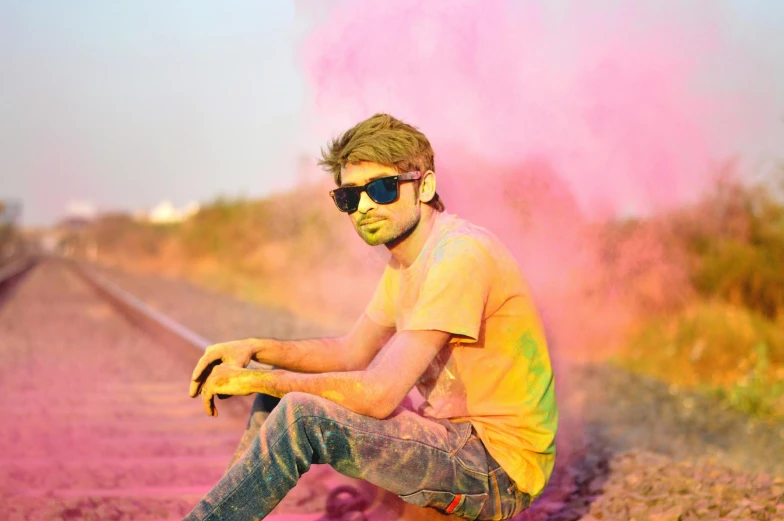 a man sitting on the side of a train track, a colorized photo, pexels contest winner, color field, holi festival of rich color, having fun. vibrant, hindu aesthetic, avatar image
