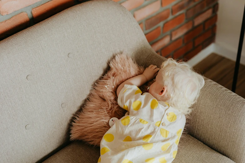 a baby sleeping on a couch with a teddy bear, by Alice Mason, pexels, lady using yellow dress, a blond, polka dot, plush furnishings