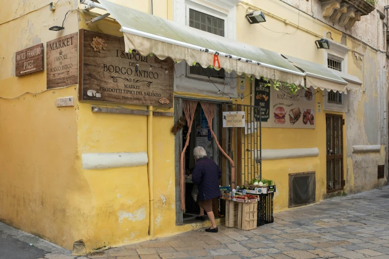 a man that is standing in the doorway of a building, arte povera, food stalls, yellowed with age, greek fabric, amaro