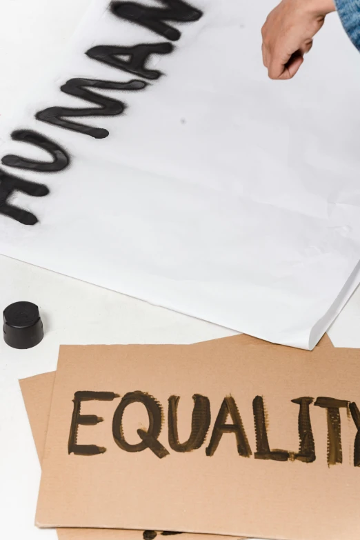 a person writing equality on a piece of paper, cut out of cardboard, thumbnail, ingredients on the table, ( ( theatrical ) )