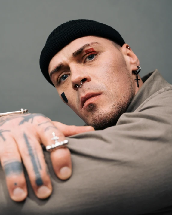 a man with a tattoo on his arm, inspired by Seb McKinnon, trending on pexels, hyperrealism, lgbt, piercing stare, hand holding cap brim, dio brando