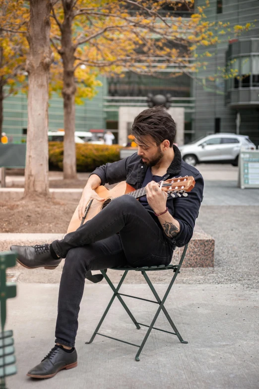 a man sitting in a chair playing a guitar, inspired by david rubín, pexels contest winner, on sidewalk, square, jay bauman, a handsome