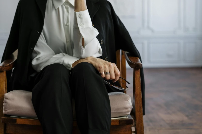 a woman sitting in a chair talking on a cell phone, by Emma Andijewska, trending on unsplash, visual art, white wrinkled shirt, wearing a tuxedo, leather cuffs around wrists, professor clothes