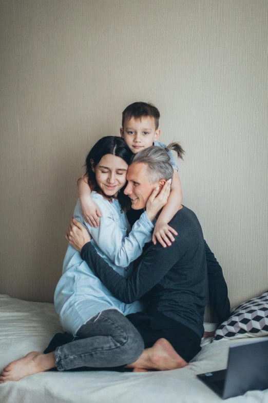 a man sitting on top of a bed next to a woman and a child, pexels contest winner, romanticism, hugging each other, excited russians, profile image, lgbtq