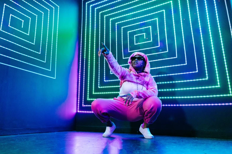 a man sitting on the ground in front of a neon wall, inspired by Zhu Da, pexels, wearing a purple sweatsuit, laser light show, lil wayne, brightly lit pink room