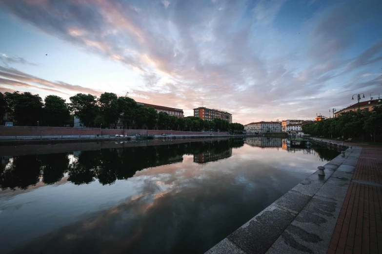 a body of water with buildings in the background, a picture, unsplash contest winner, hyperrealism, calm evening, canal, skies, southern european scenery