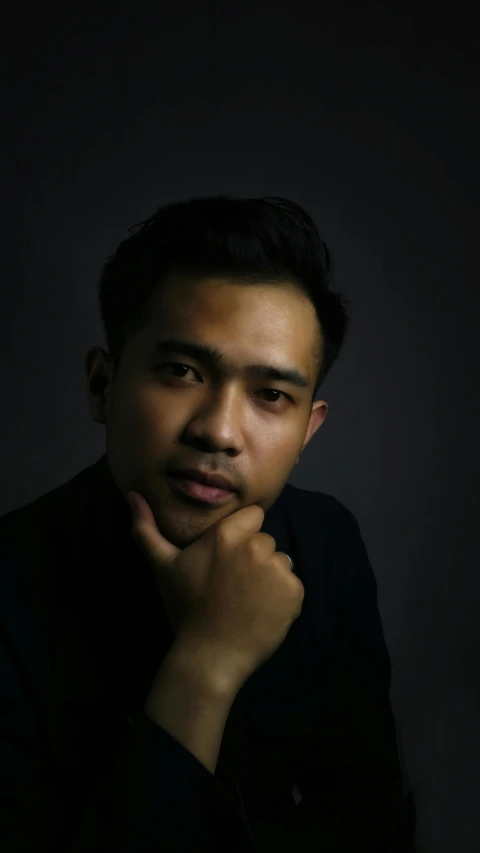 a man that is sitting down with his hand on his chin, a character portrait, by Basuki Abdullah, pexels contest winner, photorealism, square masculine jaw, dark. studio lighting, headshot profile picture, black main color
