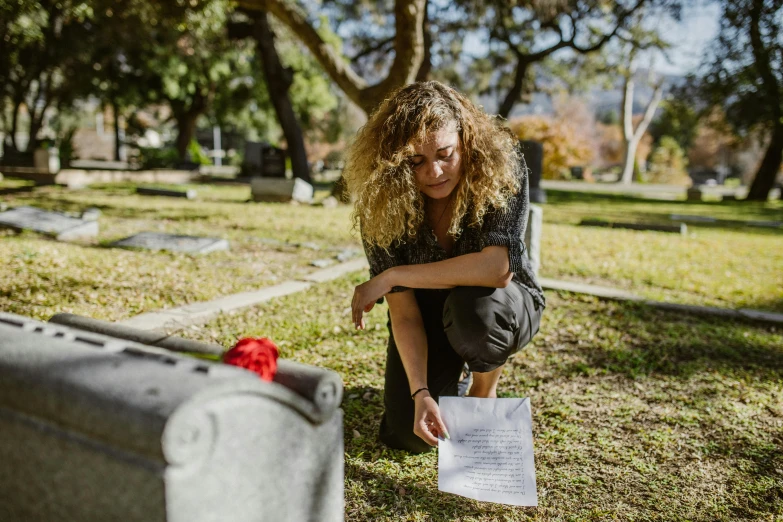 a woman kneeling in a cemetery looking at a piece of paper, a portrait, by Meredith Dillman, pexels, avatar image, contain, tear, sydney hanson