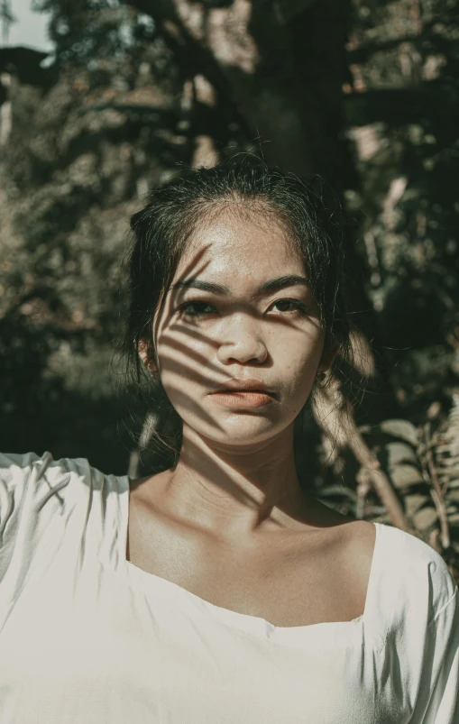 a woman covering her face with her hands, inspired by Ruth Jên, pexels contest winner, sumatraism, shadows from trees, young cute wan asian face, looking serious, striped