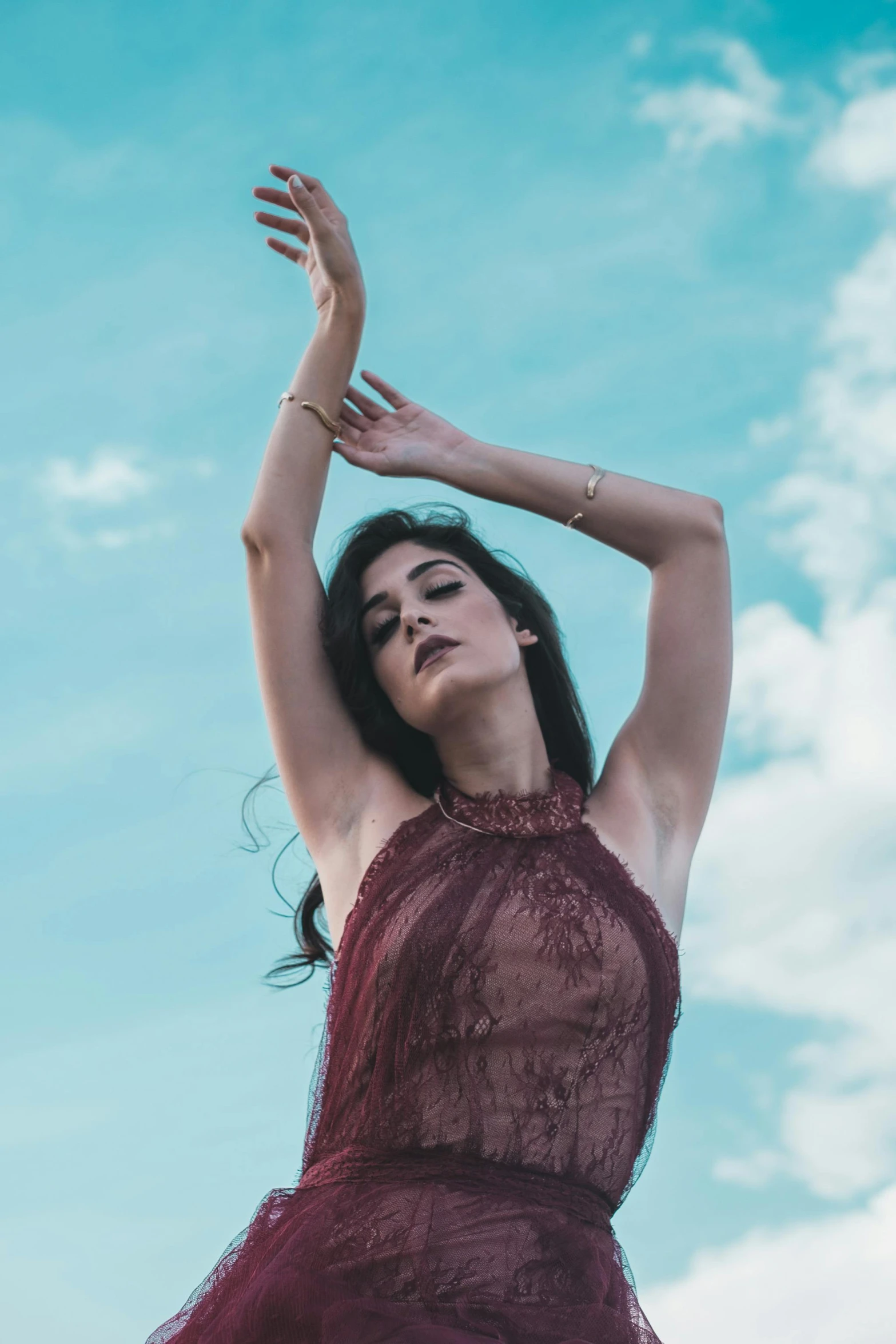 a woman standing on top of a lush green field, an album cover, inspired by Elsa Bleda, pexels contest winner, renaissance, red body suit, blue sky, brunette, photo of a hand jewellery model