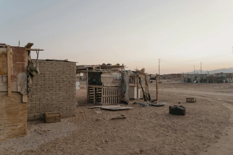 a small shack sitting in the middle of a dirt road, by Daniel Lieske, les nabis, arab ameera al taweel, crates and parts on the ground, street corner, sunfaded