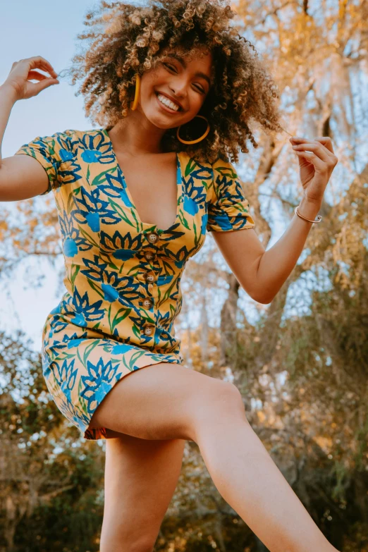 a woman jumping in the air on a skateboard, by Jessie Algie, trending on pexels, arabesque, yellow ornate dress, party in jungles, smiling seductively, low cut dress