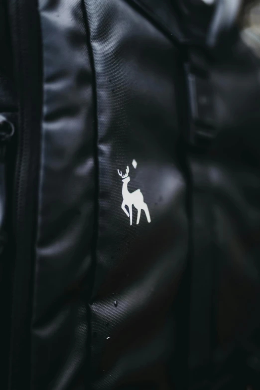 a close up of a backpack with a deer on it, unsplash, graffiti, all black matte product, tonal topstitching, pearlescent skin, brand mark