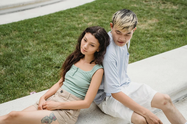 a man and a woman sitting next to each other, trending on pexels, realism, sea - green and white clothes, of taiwanese girl with tattoos, nonbinary model, people on the ground