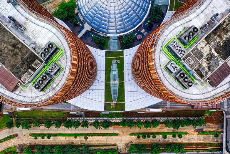 an aerial view of a building with a circular roof, by Ibrahim Kodra, pexels contest winner, two giant towers, uhd hyperdetailed photography, singapore, building cover with plant