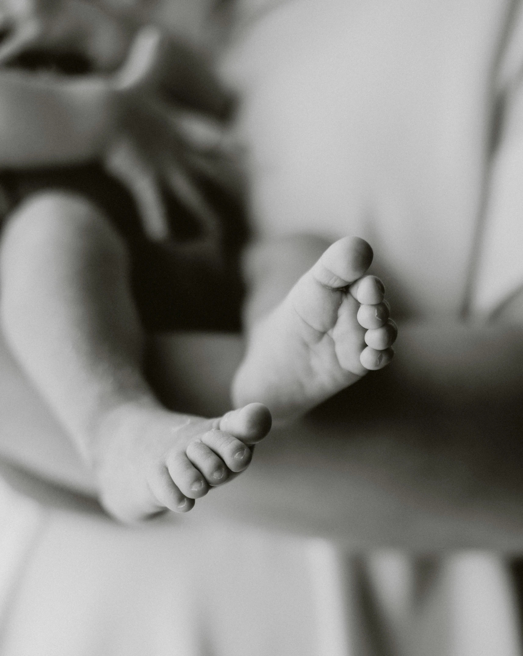 a woman holding a baby in her arms, a black and white photo, by Carey Morris, pexels contest winner, focus on his foot, lgbtq, thumbnail, a photo of sephiroth