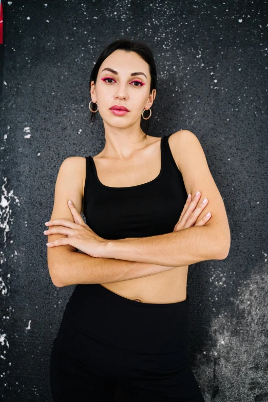 a woman in a black dress standing with her arms crossed, trending on pexels, wearing a cropped black tank top, woman in streetwear, symmetry!! portrait of a woman, bella poarch