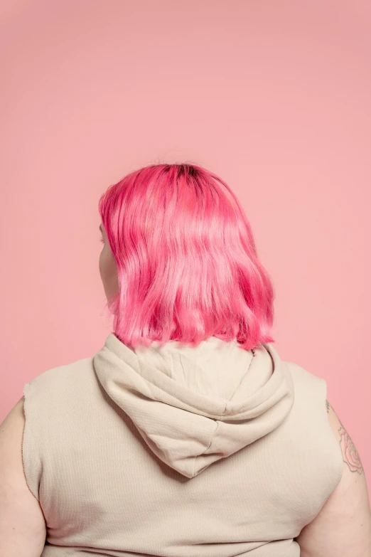 a woman with pink hair standing in front of a pink wall, trending on pexels, from the back, plain background, color image, chin-length hair