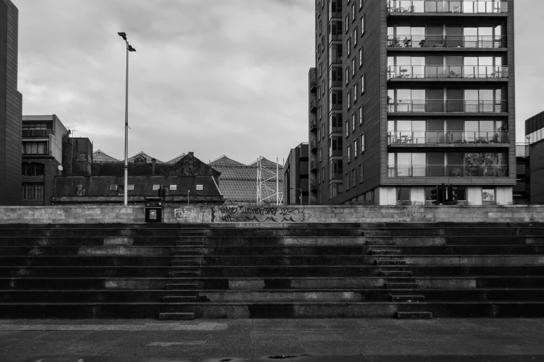 a black and white photo of some stairs, inspired by Thomas Struth, unsplash, brutalism, buildings in the distance, at the waterside, in a square, glasgow