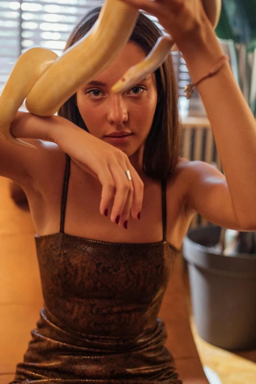a woman holding a banana over her head, inspired by Elsa Bleda, trending on pexels, renaissance, wearing a low cut tanktop, sitting on a mocha-colored table, arms made out of spaghetti, isabela moner