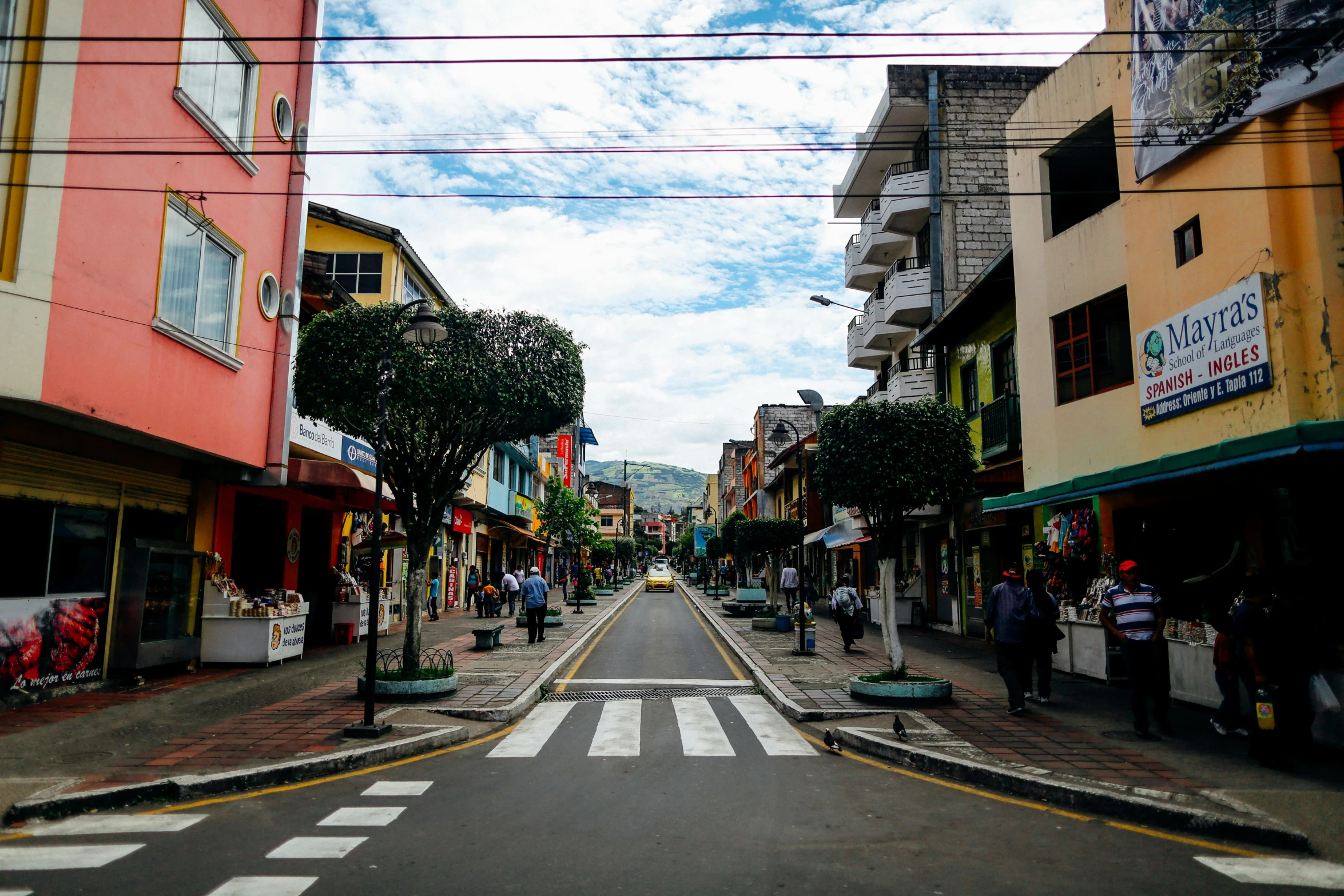 a street filled with lots of shops next to tall buildings, an album cover, unsplash, quito school, square, reunion island, lush paradise, ground - level medium shot