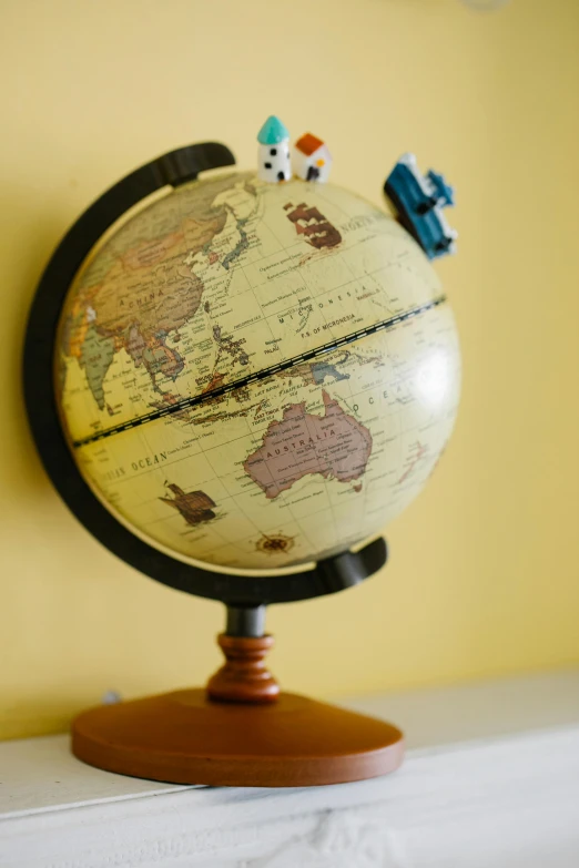 a close up of a globe on a table, toy room, yellow, ivory, hero shot