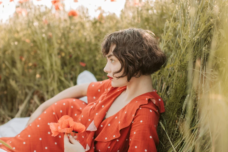 a woman laying on a blanket in a field of flowers, an album cover, pexels contest winner, red jumpsuit, with a bob cut, polka dot, profile image