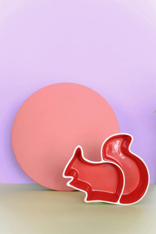 a red squirrel cookie cutter sitting on top of a table, pop art, plates, pink studio lighting, circle, curated collection