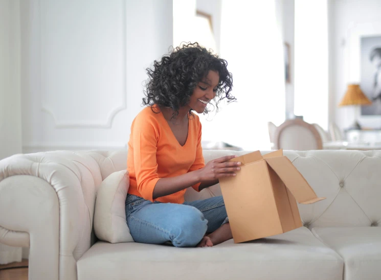 a woman sitting on a couch opening a box, ashteroth, at checkout, transforming, uploaded