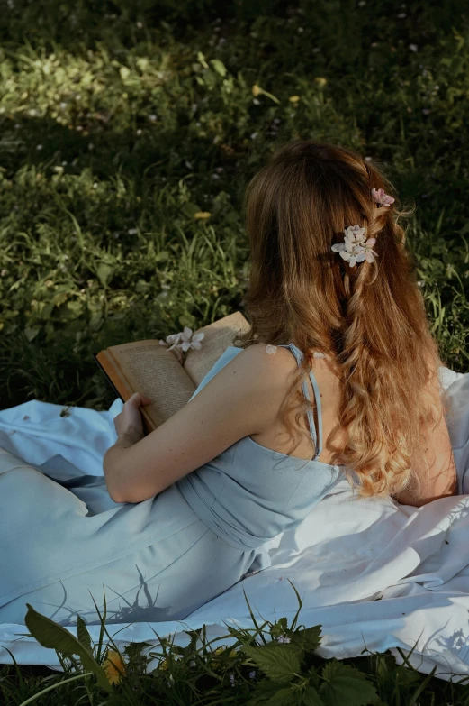 a woman sitting on a blanket reading a book, inspired by Konstantin Somov, pexels contest winner, renaissance, flowers on hair, light blue dress portrait, back lit, long hairstyle