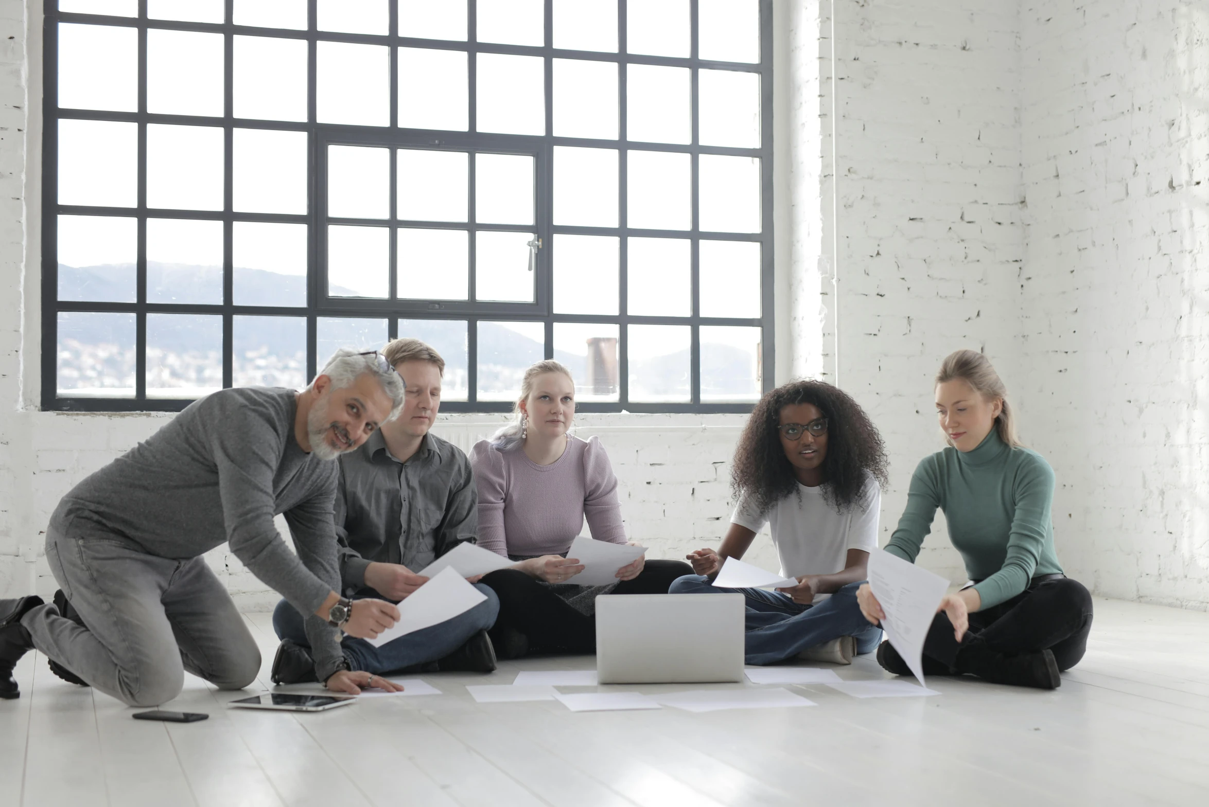 a group of people sitting on the floor around a laptop, agile, hr geiger design, thumbnail, grey