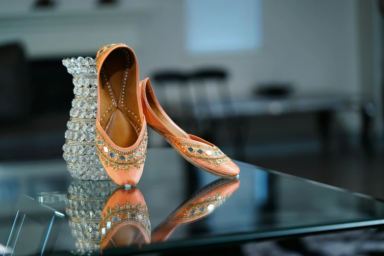 a pair of shoes sitting on top of a glass table, of indian princess, peach embellishment, shot with sony alpha 1 camera, mirroring