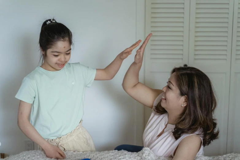 a little girl sitting on top of a bed next to a woman, pexels contest winner, hurufiyya, greeting hand on head, casual game, te pae, idealised