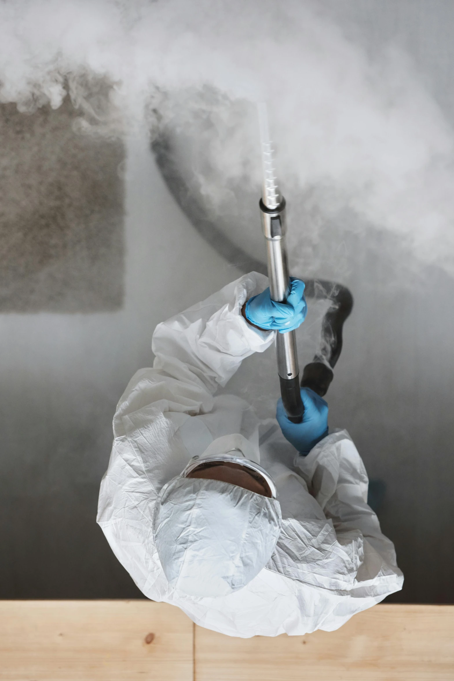 a person spraying something with a spray gun, by Ben Zoeller, shutterstock, process art, cryogenic pods, smoke filled room, clean medical environment, gray